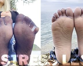 Feet tease in black and grey nylon socks wiggling toes at the seashore